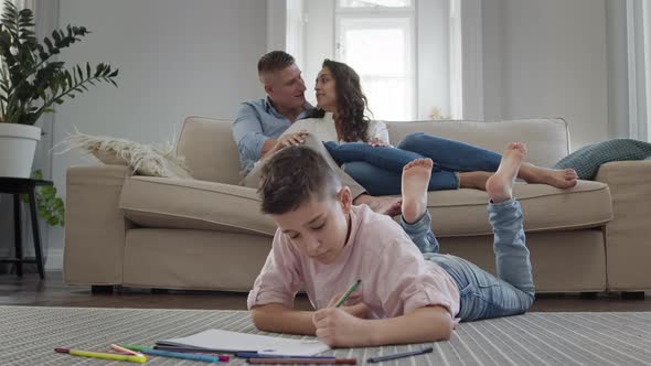 Boy Lies On The Floor In The Room And Draws On Piece Of Paper