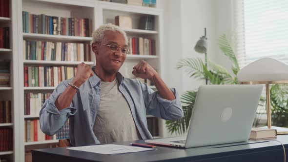 Happy African Man on Laptop Celebrates Successful Endeavor with YES Gesture