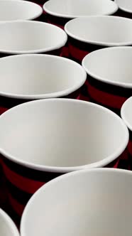 Row Red and Black Disposable Paper Cup for Coffee or Hot Beverage on Dark Backdrop Rotate Slowly