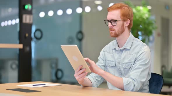 Serious Professional Casual Redhead Man Using Tablet in Office 