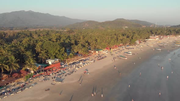 People stroll along Palolem beach sand and calming sea waves, Goa, India