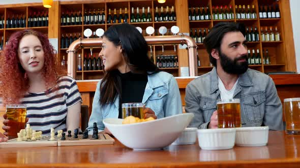 Friends playing chess while having glass of beer in bar 4k