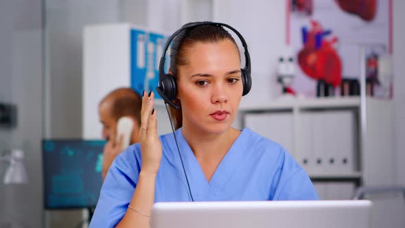 Doctor Assistant Using Headphones in Hospital Answering To Patients Calls