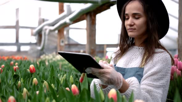 A Woman Florist in a Hat Uses a Tablet to Scan the Health of Flowers