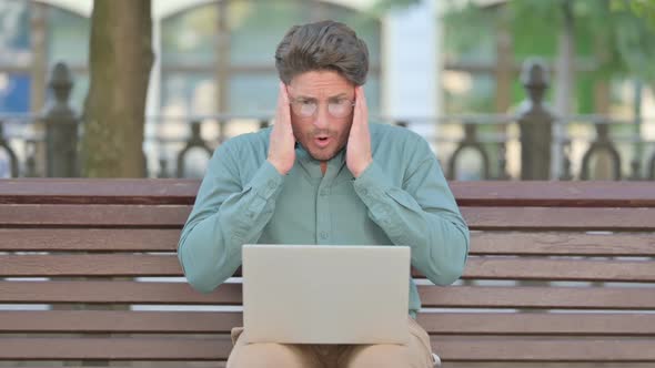 Middle Aged Man Feeling Shocked While using Laptop, Outdoor