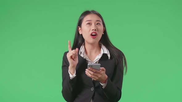 Asian Business Woman Thinking Then Raising Index Finger While Using Mobile Phone In The Green Screen