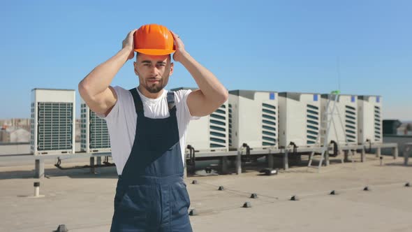 Portrait of an Engineer Who is Putting a Protective Helmet on His Head