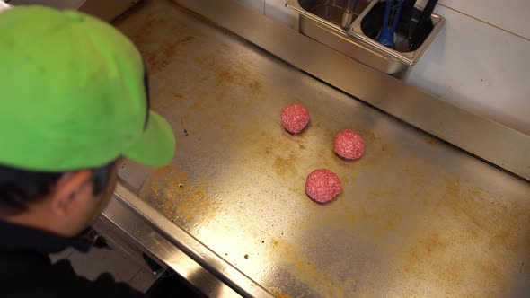 Professional Cook Preparing Raw Hamburger Meat on a Hot Plate in Commercial Restaurant