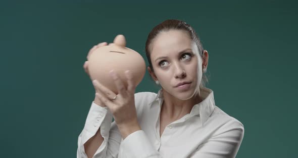 Young businesswoman holding a clay money box and smiling, saving money and investments concept