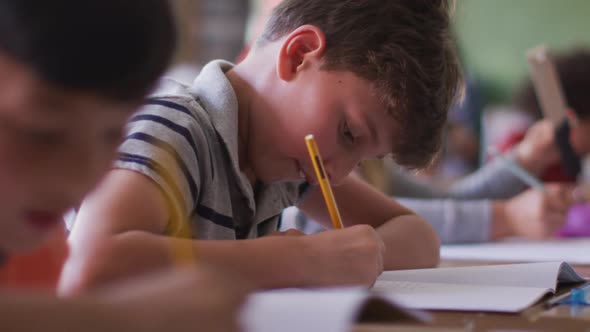 Two boys writing while sitting on their desk at school