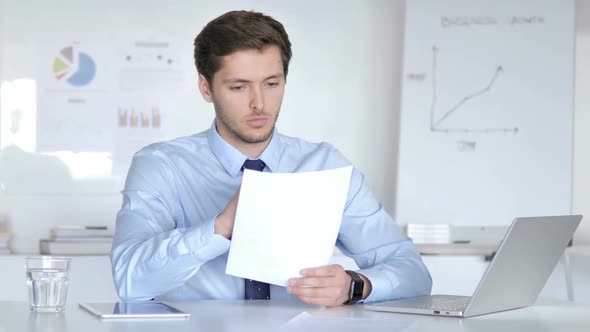Pensive Businessman Reading Documents at Work