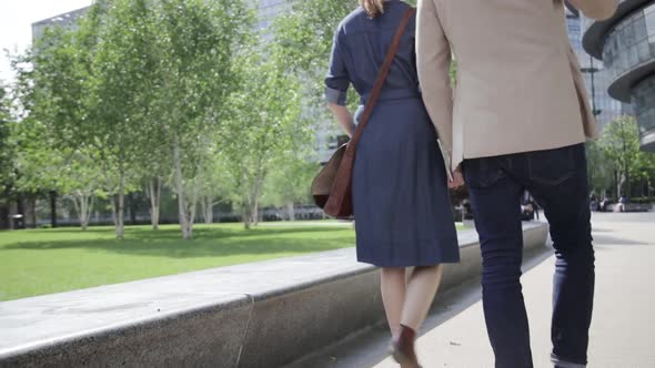 Two colleagues walking outside of office building, rear view