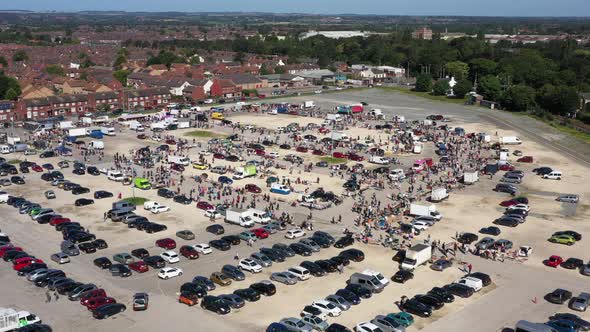 Aerial pull away and rise up from a busy market and car boot sale in Hull, England UK