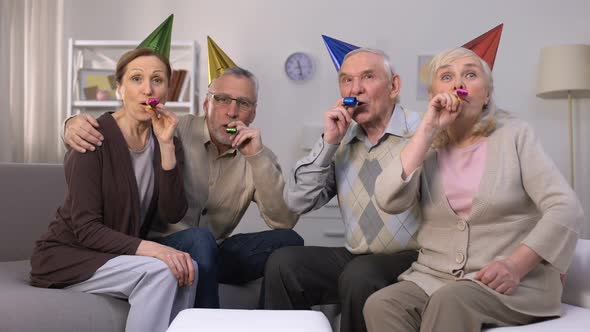 Cheerful Aged People in Birthday Hats Blowing in Party Horn, Celebration, Party