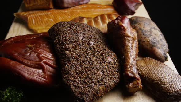 Rotating shot of a variety of delicious, premium smoked meats on a wooden cutting board