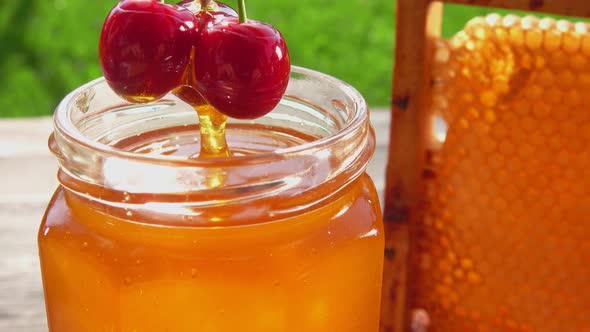 Closeup of Large Cherries on the Twig Dipped Into Fresh Honey in a Glass Jar