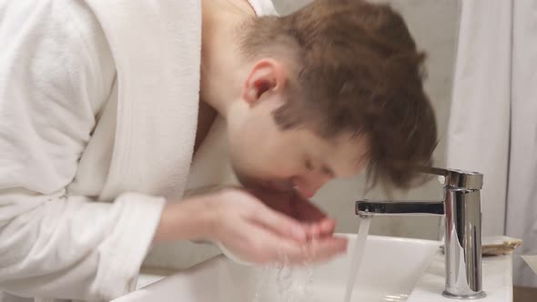 Man Performs Morning Routines Washes His Face in the Bathroom