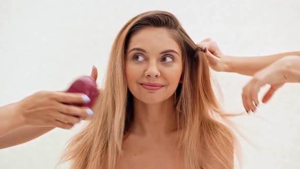 Hands Combing Hair of Young Beautiful Naked Girl in Towel Over White Background