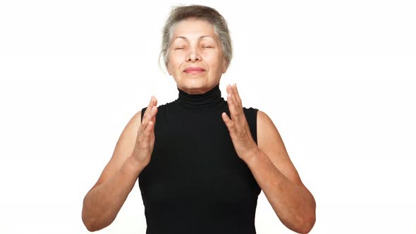 Happy Female Pensioner with Gray Tied Hair Meditating in Front of Camera Taking Deep Breaths