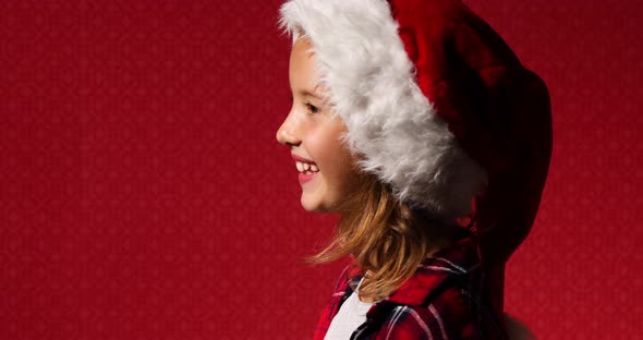 Christmas Portrait side view of little Girl in Santa Hat, smiling child sings a song