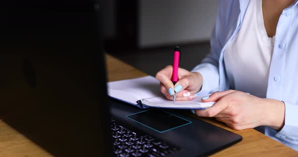 Female Making Notes in Planner While Working on Remote Project in Home Office