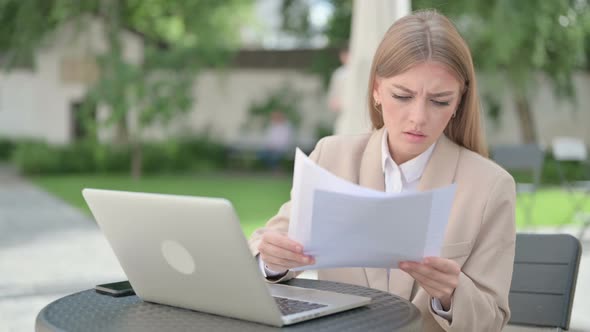 Young Businesswoman with Laptop Celebrating While Reading Documents