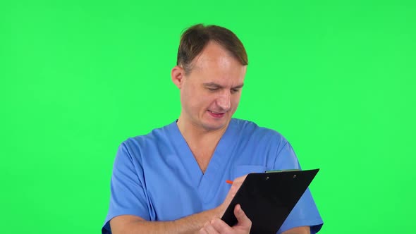 Medical Man Thinks, Speaks and Writes at Black Folder with Pensil. Green Screen