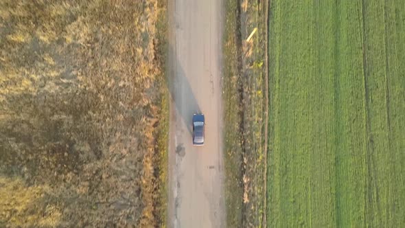 Top down aerial view of a car driving fast on bad road with potholes.