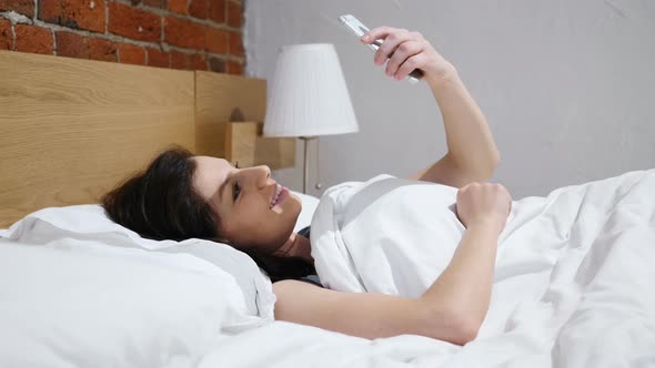 Woman Taking Selfie in Bed, Front Camera View