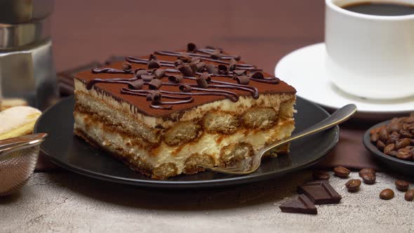 Portion of Traditional Italian Tiramisu dessert, cup of espresso and mocha coffee maker