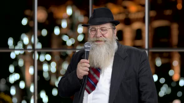 Cheerful Man in Business Suit Talking Into Microphone
