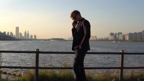 Man in sunglasses watches phone on the beautifull  sunset background