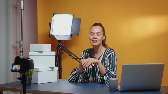 Influencer Talking to Camera and Giveaway Boxes are on the Desk