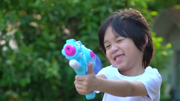 Cute Asian Child Playing With Water Gun In The Summer