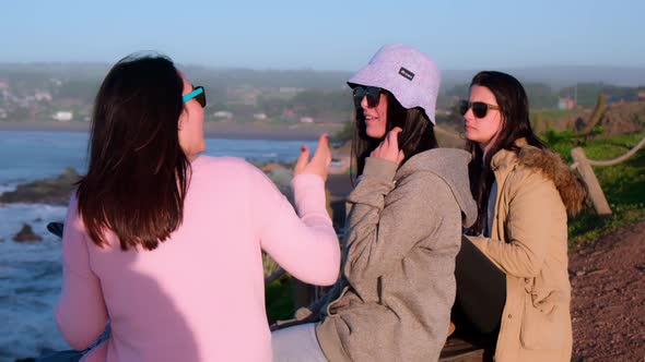 group of three women travelers and friends talking while looking at the sea, pichilemu
