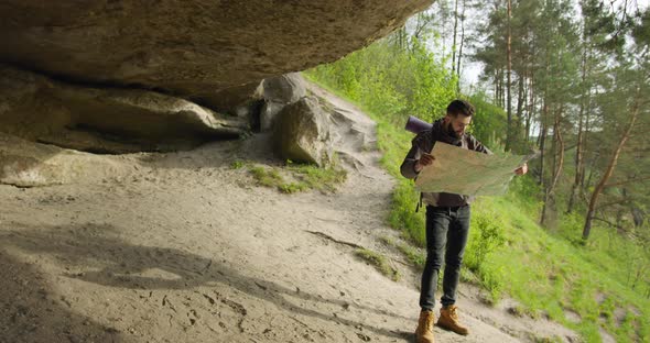 The Guy Is Standing Under the Big Rock and Checking the Route