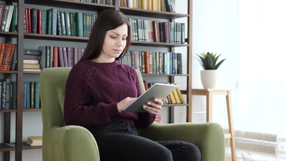 Woman Sitting on Casual Chair Browsing Internet on Tablet