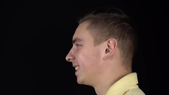 The Man Received a Balloon in the Face with Water. A Young Man Stands on a Black Background. A