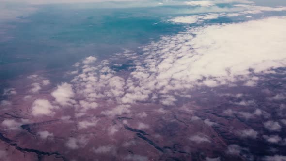 High altitude aerial flying over a desert landscape above the cloud cover.