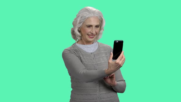 Mature Woman Taking Selfie on Color Background