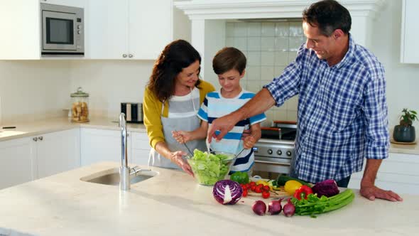 Parents and son mixing the salad in kitchen