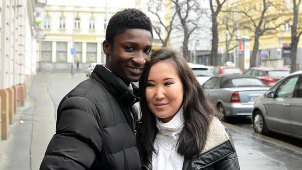 Happy Couple Kiss and Smile To Camera - Black Man and Asian Woman - Urban Street with Cars - City