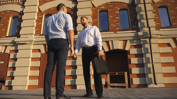 Young Male Coworkers Talks Standing Near Office Building at City