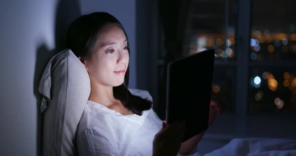 Woman use of mobile phone and lying on bed at night