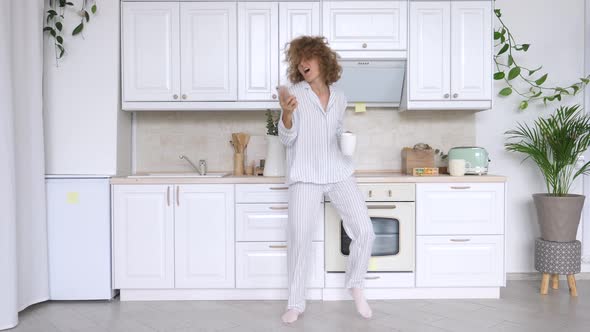 People And Technology Concept. Happy Woman With Smart Phone, Dancing And Smiling In Kitchen