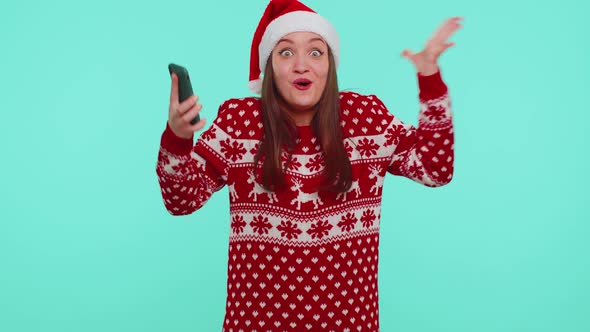 Young Teen Girl in Christmas Sweater Looking Smartphone Display Sincerely Rejoicing Win Success Luck