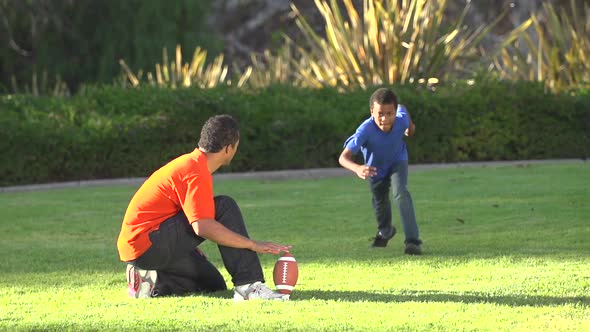 A father teaching his sons how to play American football.