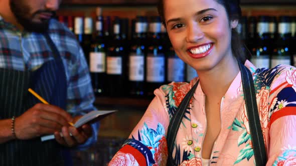 Portrait of smiling barmaid with barman in background