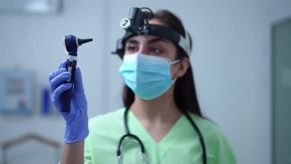 Otoscope in Hand of Blurred Caucasian Female Otolaryngologist Standing in Hospital Indoors