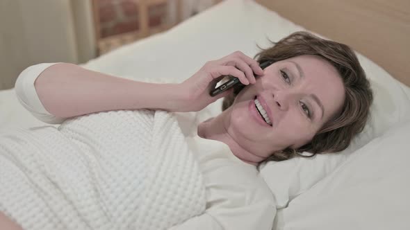 Attractive Old Woman Talking on Smartphone in Bed 